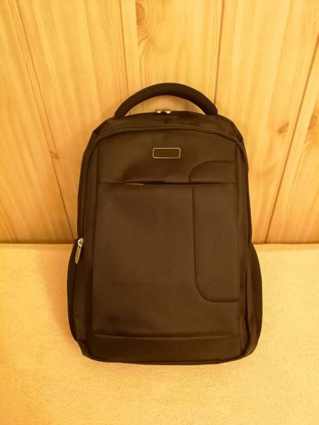 istock Dark brown backpack, with handle and zippers, leaning against wooden paneling 1212245369