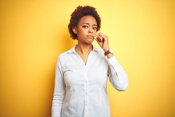 african american business woman over isolated yellow background mouth and lips shut as zip with fingers. secret and silent, taboo talking - silence finger on lips businesswoman one person imagens e fotografias de stock