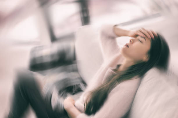 Sick woman with headache feeling faint vertigo holding head in pain with fever and migraine. Blurry motion blur background stock photo