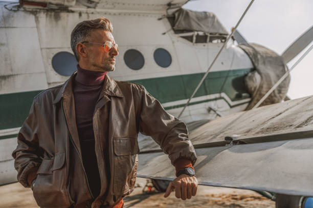istock Stylish guy wearing leather jacket near plane 1212250017