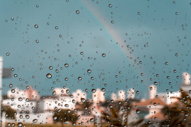 istock A rainbow over some buildings behind a glass windows with water drops. 1212252976