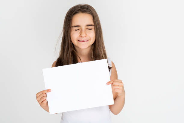 istock Child girl smiling holding white sheet blank isolated 1212258290