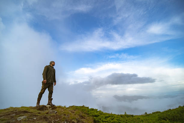 istock The man standing on the mountain on the white clouds background 1212259198