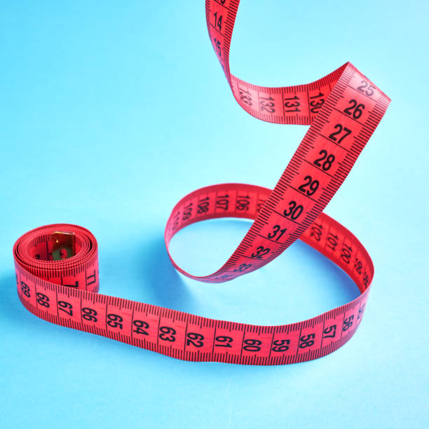 istock weight loss measuring concept. red centimeter with balancing pen over blue background. 1212259270