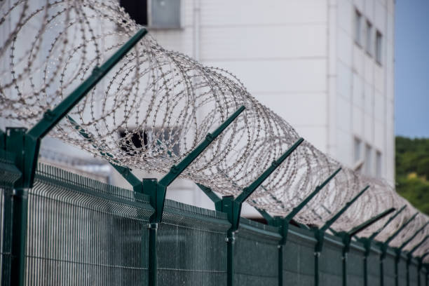 wervelingen van prikkeldraad over het hek. hek symboliseert gevangenis, niet-vrijheid, totalitarisme en verboden. - prison stockfoto's en -beelden