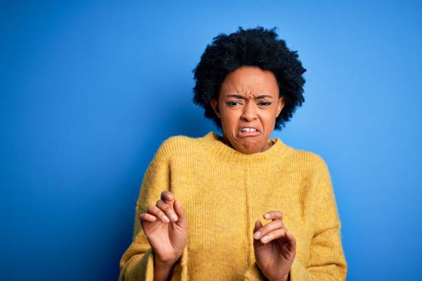 junge schöne afroamerikanische afro-frau mit lockigen haaren trägt gelben lässigen pullover ekelhaft enkel, unzufrieden und ängstlich tun ekel gesicht, weil aversion reaktion. - offense stock-fotos und bilder