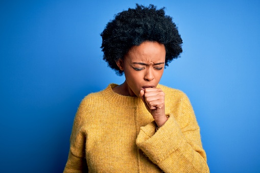 Young beautiful African American afro woman with curly hair wearing yellow casual sweater feeling unwell and coughing as symptom for cold or bronchitis. Health care concept.
