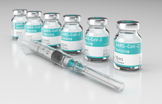 Syringe with Row of Vials of Coronavirus Vaccine on Shiny White