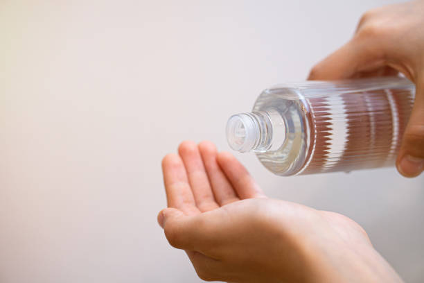 pessoa derramando colônia em suas mãos para limpeza pessoal das mãos - nail polish isolated cosmetics bottle - fotografias e filmes do acervo