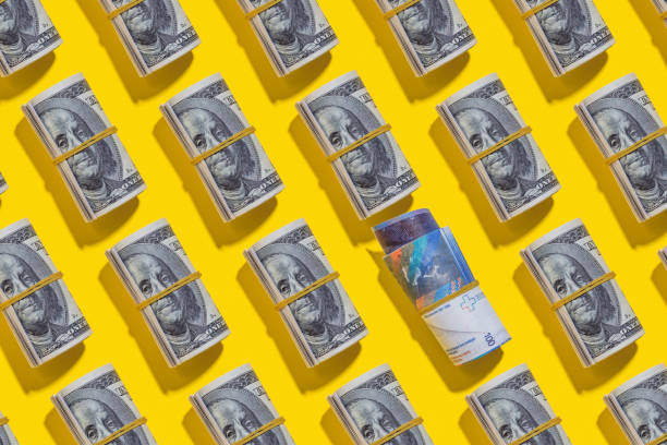 istock Swiss franc and American dollar rolls on yellow background 1212263146