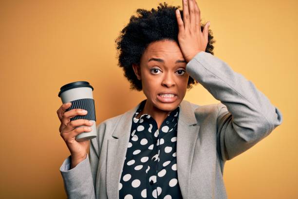 곱슬 머리 마시는 커피 한 잔을 가진 젊은 아프리카 계 미국인 아프로 사업가는 부끄러움과 깜짝 얼굴에 충격을 받고, 화가 나서 좌절했습니다. 실수에 대한 두려움과 화가. - confusion hand in hair tired touching 뉴스 사진 이미지