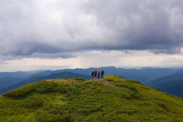 istock The four people with backpacks standing on a mountain against beautiful clouds 1212263380