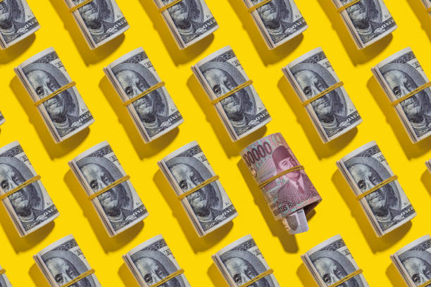 istock Indonesian rupiah and American dollar rolls on yellow background 1212263909