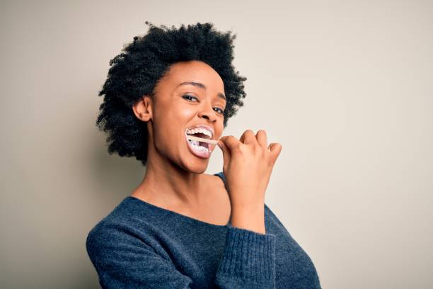 donna afroamericana che si lava i denti usando spazzolino da denti e pasta orale, pulendo denti e lingua come sana routine mattutina di assistenza sanitaria - healthy lifestyle human teeth adult brushing foto e immagini stock