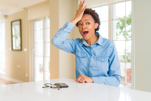 istock Young beautiful african american woman surprised with hand on head for mistake, remember error. Forgot, bad memory concept. 1212265689