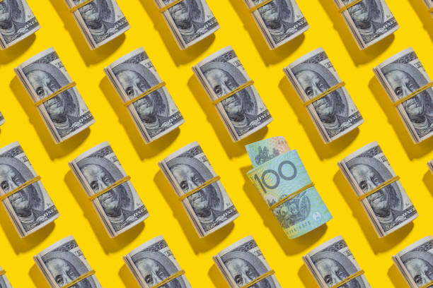 istock Australian dollar and American dollar rolls on yellow background 1212267423