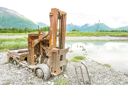 An antique forklift sits abandoned on the shores of Prince William Sound harbor.  The fork lift is a reminder of days gone by. Now it has become a part of the scenic beauty that can be found at the location of Valdez, before the Great Earthquake.