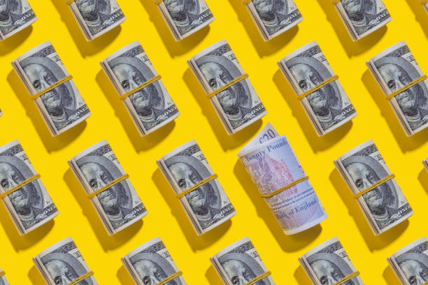 istock British pound and American dollar rolls on yellow background 1212268469