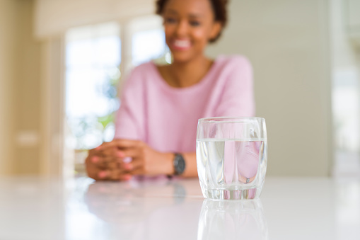 Beautiful young african american woman drinking a glass of fresh water
