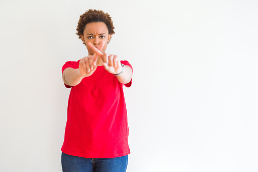 Young beautiful african american woman over white background Rejection expression crossing fingers doing negative sign