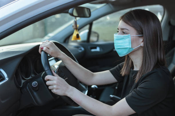 istock Woman driving car while wearing protective mask 1212272711