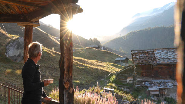 istock Mature man relaxes outside mountain hut at sunrise 1212282468