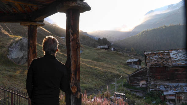 istock Mature man relaxes outside mountain hut at sunrise 1212282486