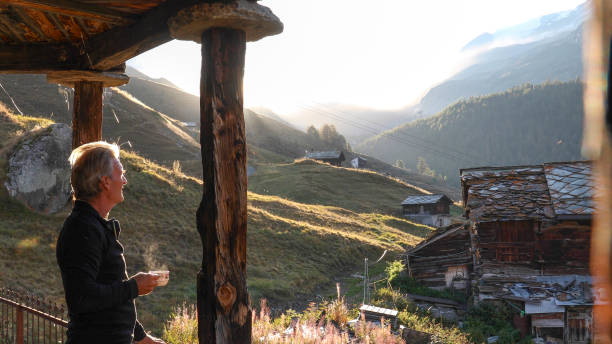 istock Mature man relaxes outside mountain hut at sunrise 1212282519