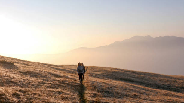 istock Friends walk through grassy meadow at sunrise 1212282532