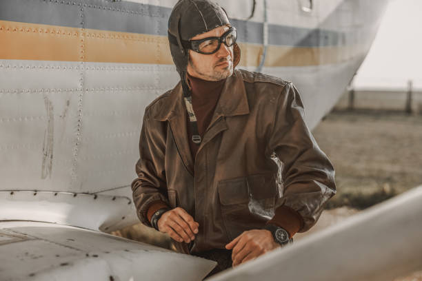 Waist up of stylish pilot standing near airplane wing stock photo