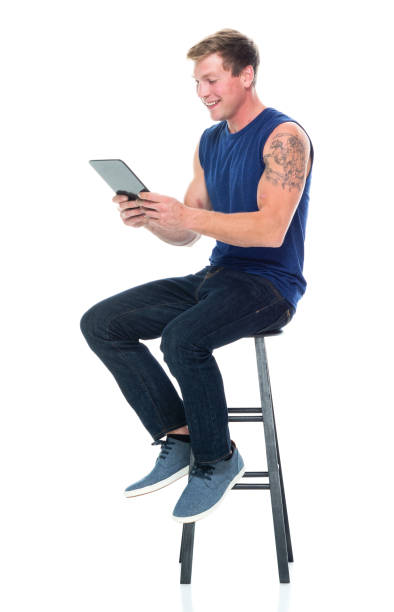 homme caucasien sans manches s’asseyant devant le fond blanc portant le débardeur et utilisant la tablette numérique - 16621 photos et images de collection
