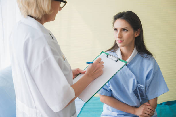 istock Senior woman doctor and patient discussing and making notes about symptom problem while she sitting on the bed. 1212307234