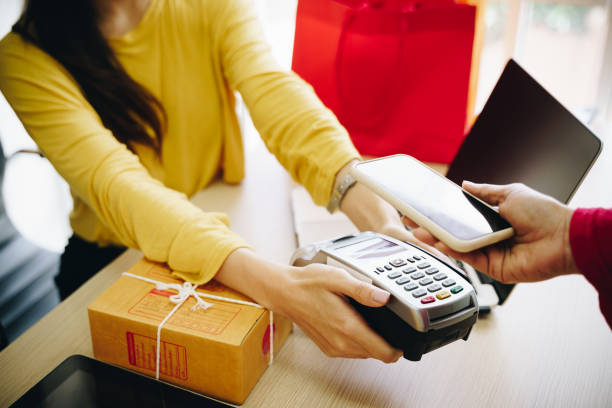 istock Closeup of hands using mobile payment with credit card machine in shop. Technology and business concept. 1212309512