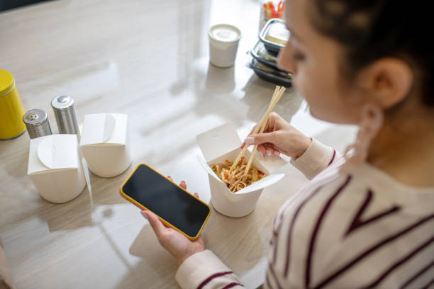 istock Beautiful woman hands holding phone and chopsticks 1212310043
