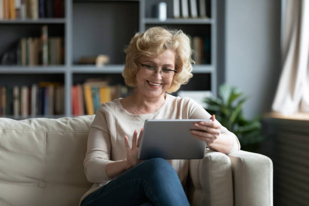 istock Middle-aged woman using tablet gadget at home 1212315789
