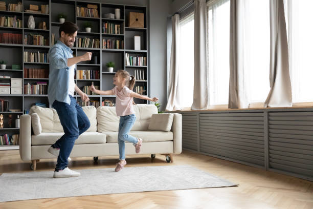 istock Overjoyed young dad and little daughter dancing at home 1212315849