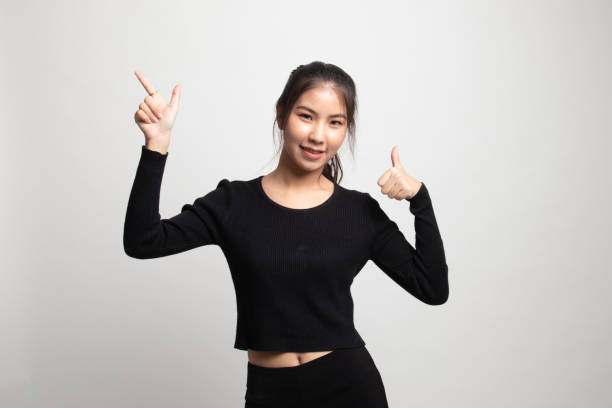 istock Young Asian woman point and thumbs up. 1212319021