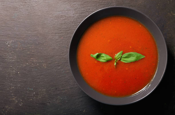 istock bowl of tomato soup with basil on dark background 1212319043