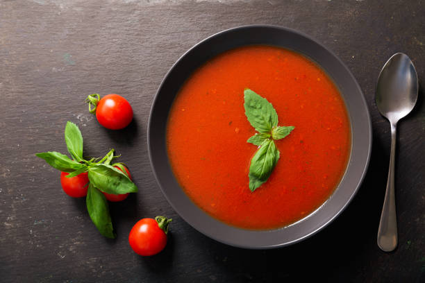 istock bowl of tomato soup with basil on dark background 1212319058