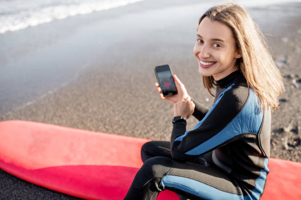 istock Relaxed surfer with surfboard and phone on the beach 1212320142