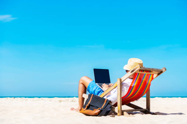 istock A man using laptop on the tropical beach on vacation. Technology for life concept. 1212320447