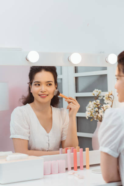 istock Young beautiful woman making make-up near mirror 1212325002