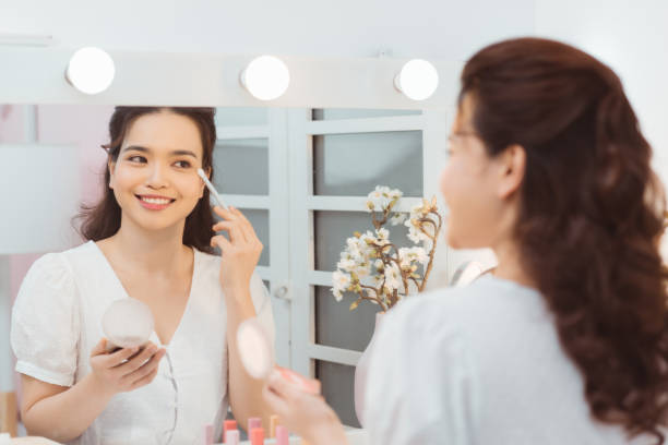 istock Young lady with pocket mirror using soft brush to smear eyeshadow 1212325195