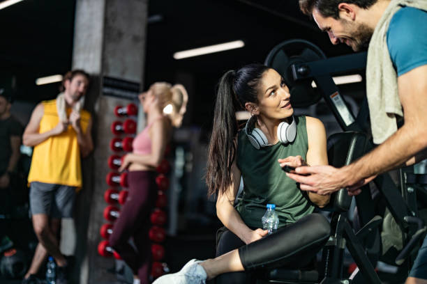 istock Happy athletic friends talking while using cell phone on a break in a gym. 1212328098