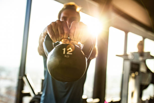 nahaufnahme des männlichen athleten, der mit einer kesselglocke in einem fitnessstudio trainiert. - crossfit kettle bell equipment weights stock-fotos und bilder