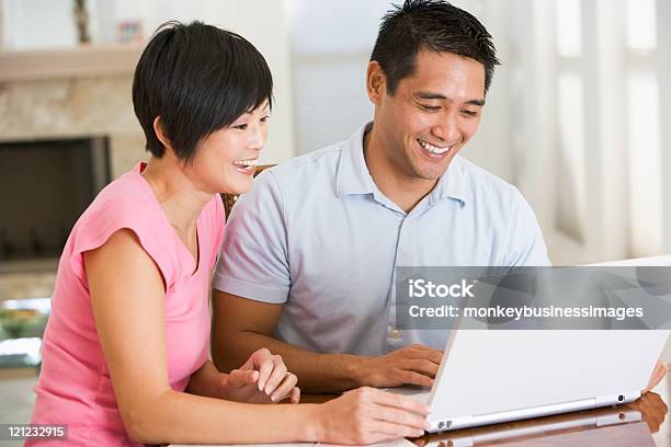 Photo libre de droit de Couple Dans La Salle À Manger Avec Ordinateur Portable Souriant banque d'images et plus d'images libres de droit de Ordinateur portable