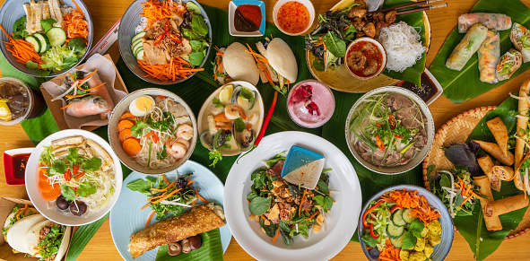 Food spread on a large table with different authentic Vietnamese dishes.