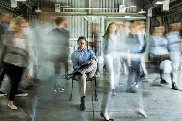 istock Businessman taking notes surrounded by his colleagues in blurred motion. 1212329459