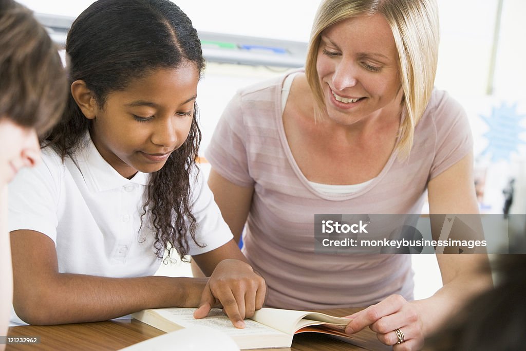 Uczennica i nauczyciel czytanie książki w klasie - Zbiór zdjęć royalty-free (Nauczyciel)
