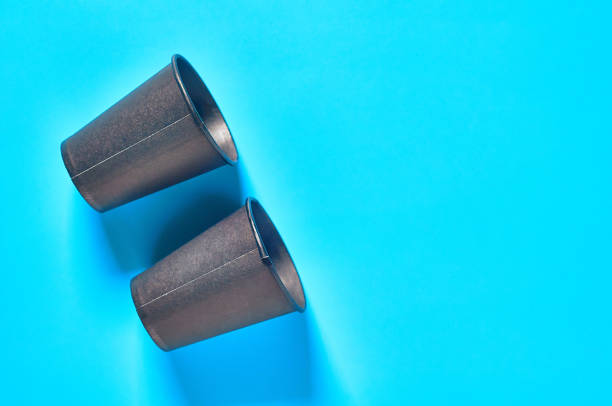 istock Two empty black cardboard glasses for hot beverages on blue background. Top view. Copy space. Concept of environmental protection, coffee break, ecology, garbage recycle 1212330245